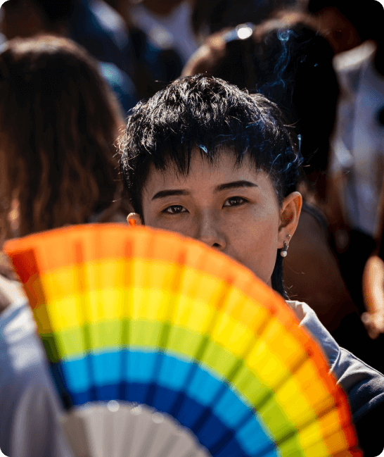 Imagem de uma pessoa com um leque de arco-íris na frente